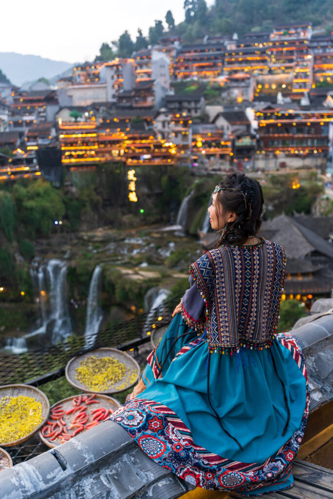 Mujer con vestimenta tradicional de la china rural, viendo la ciudad de Lijang