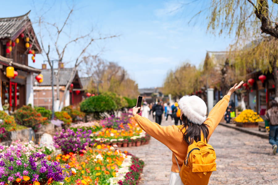 Fotografía de turista en Yunnan China a lado de un campo de flores